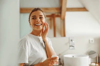 Woman smiling applying skin care after laser skin treatment in Los Altos, CA